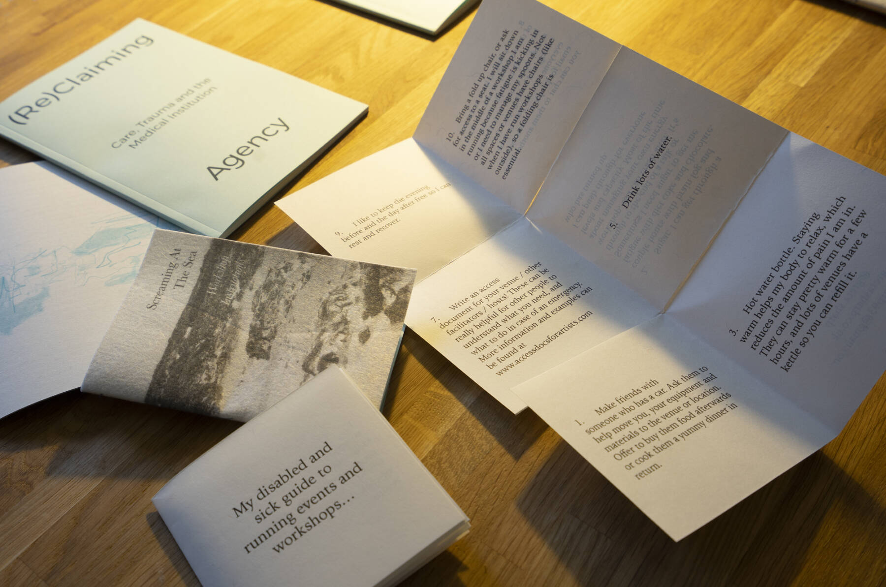 [collection of zines open on a table at an exhibtion]
